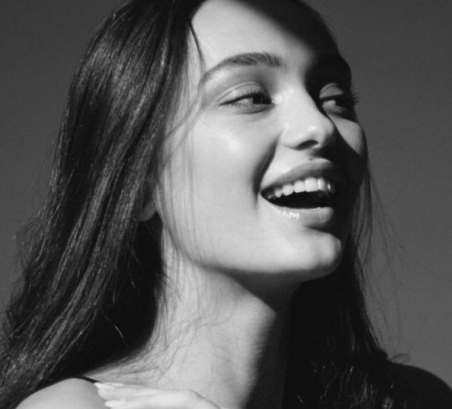 Smiling woman with long hair in black and white.