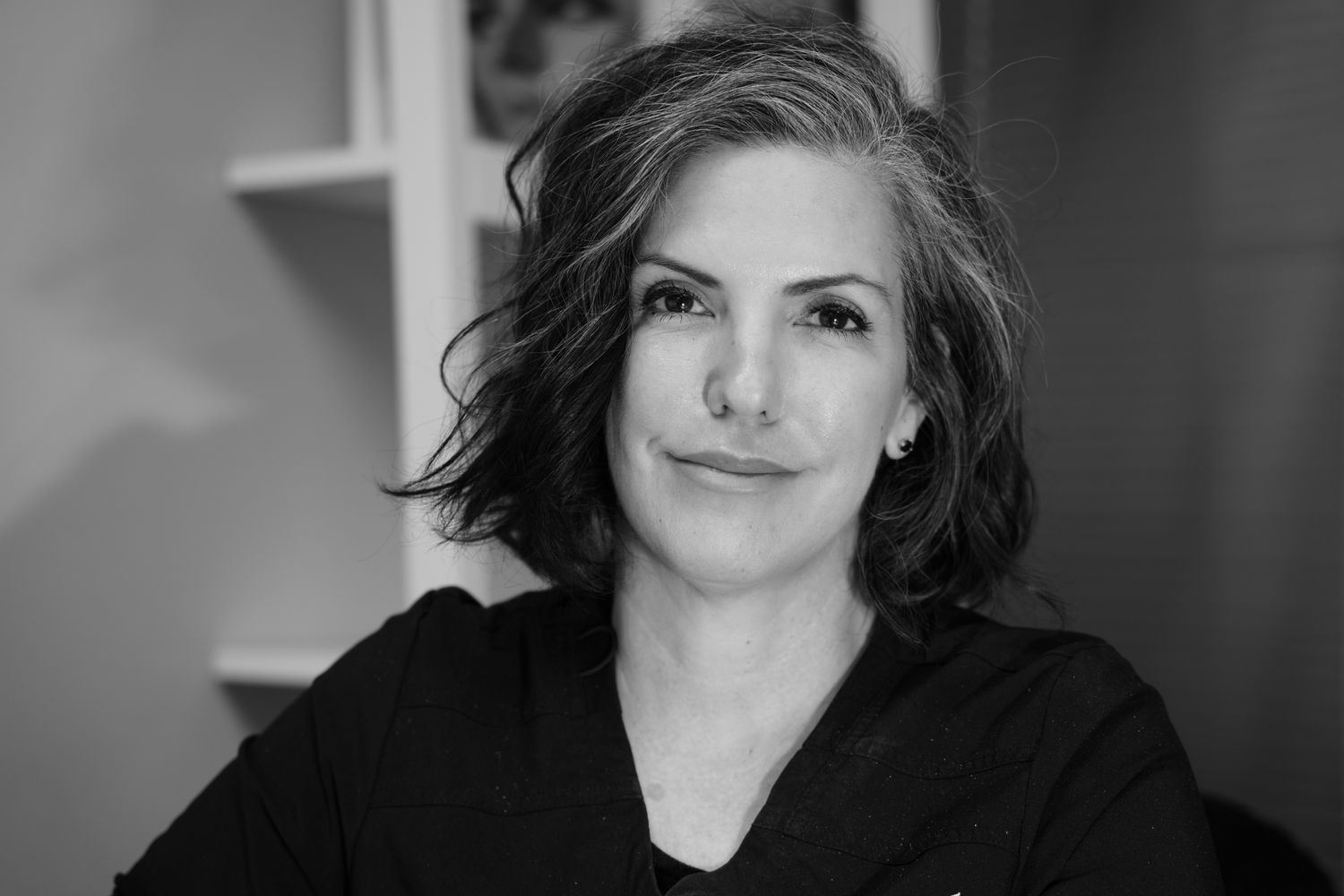 Professional woman with curly hair, smiling calmly.