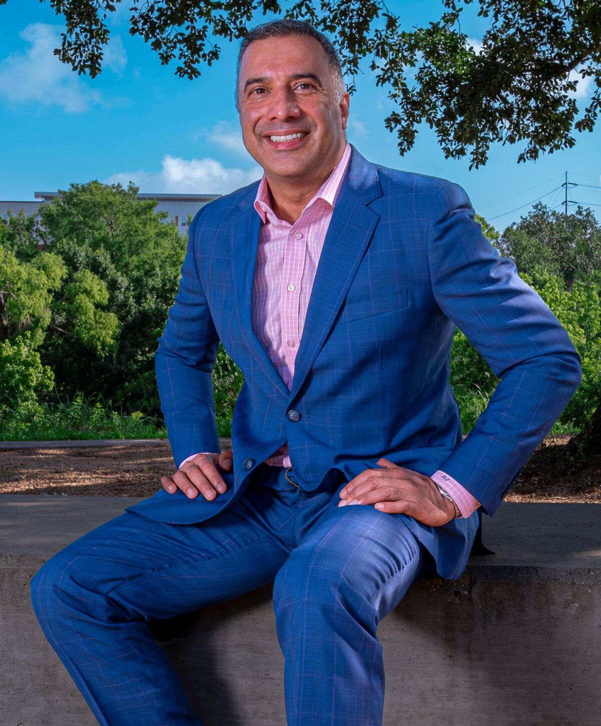Smiling man in blue suit outdoors.