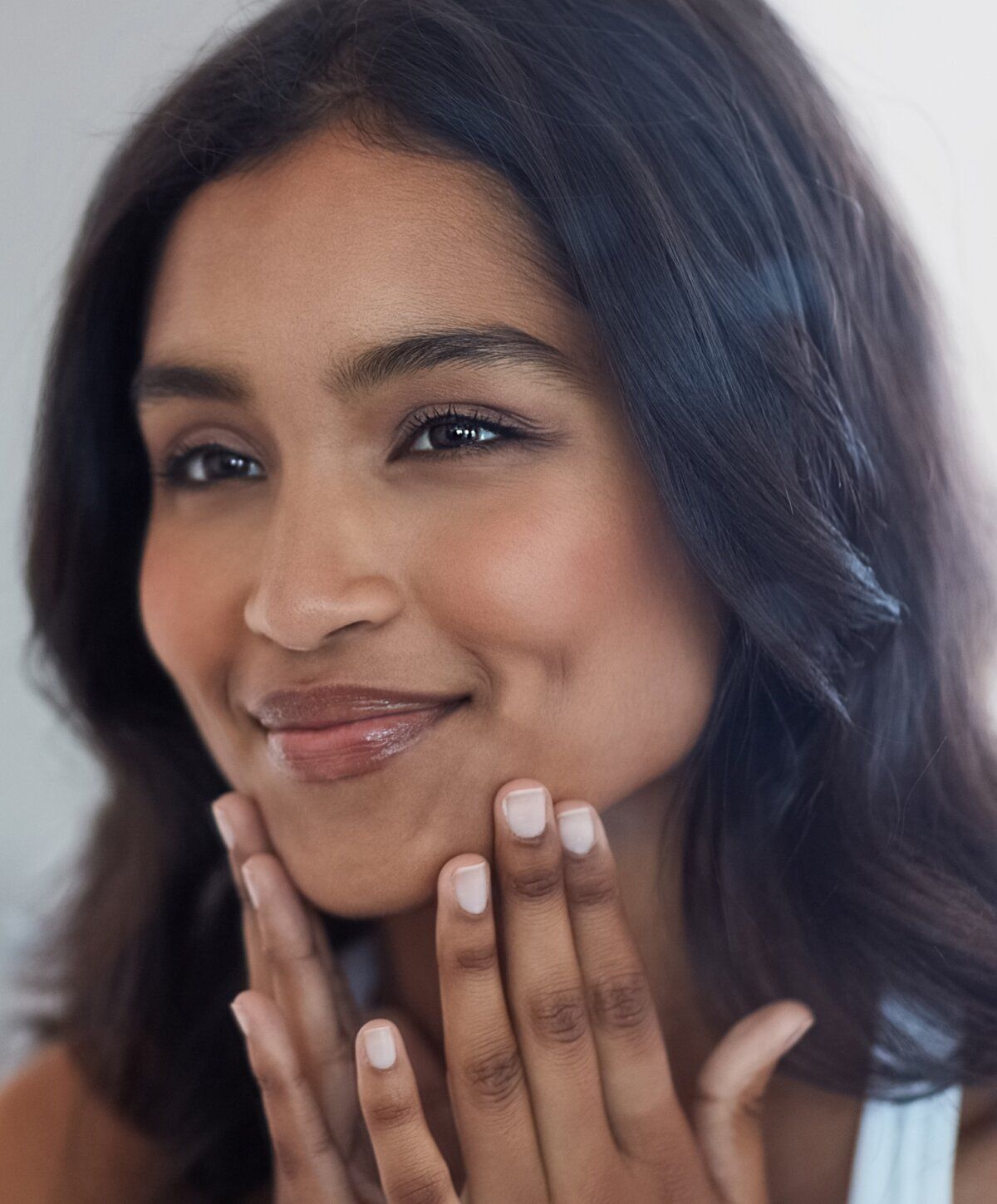 Smiling woman with hand on chin against gray background