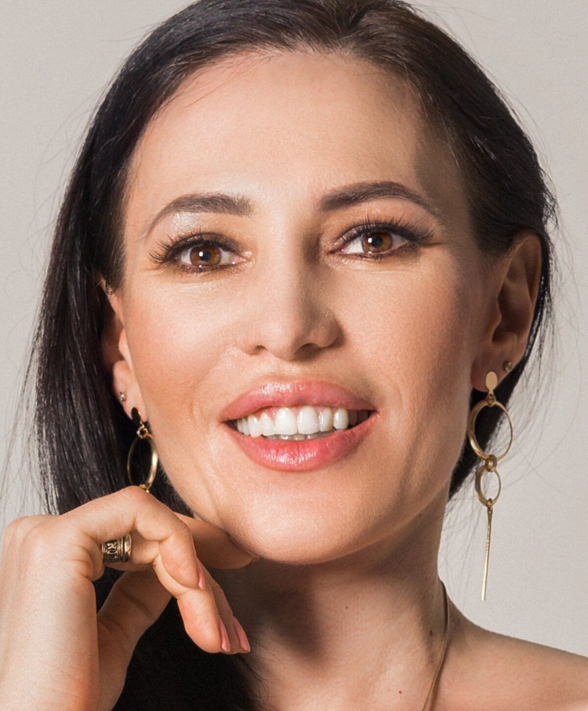 Smiling woman with jewelry and long hair.