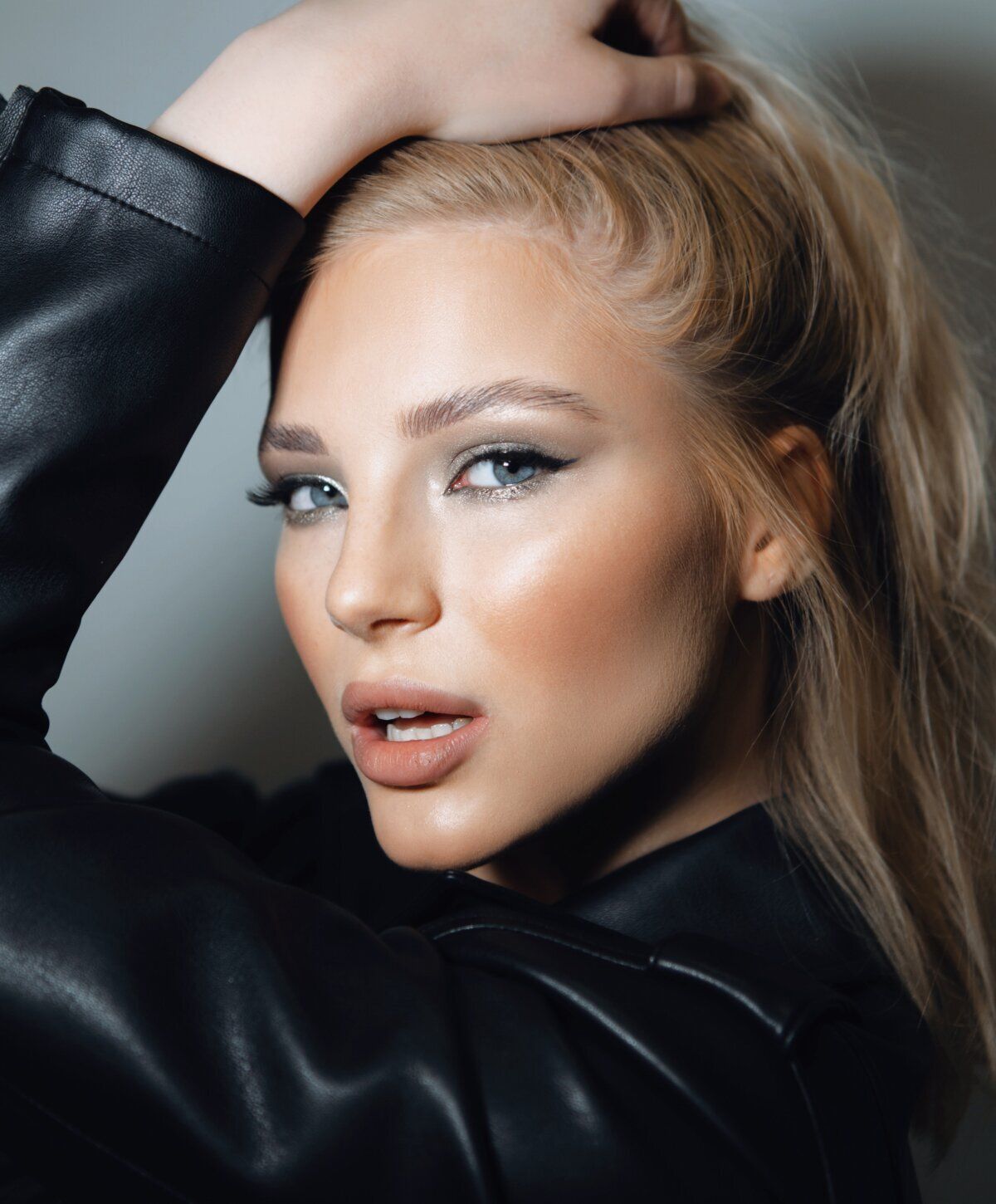 Blonde woman with striking makeup and leather jacket.