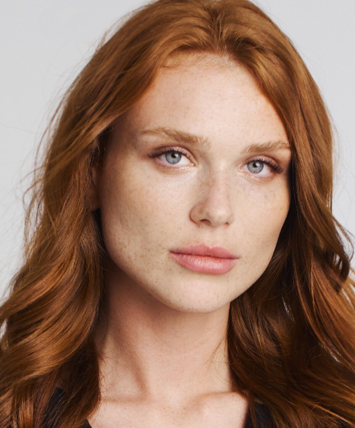 Portrait of a woman with red hair and freckles.