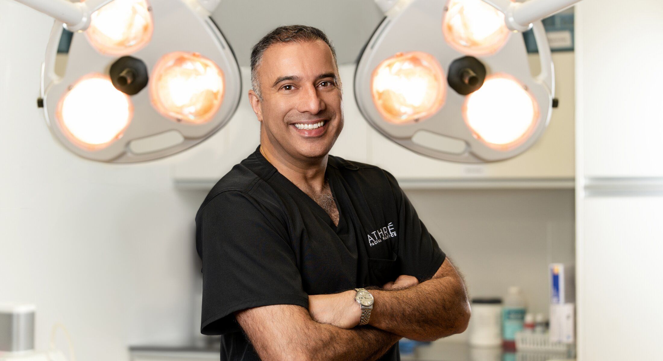 Smiling doctor in surgical scrubs, medical setting.