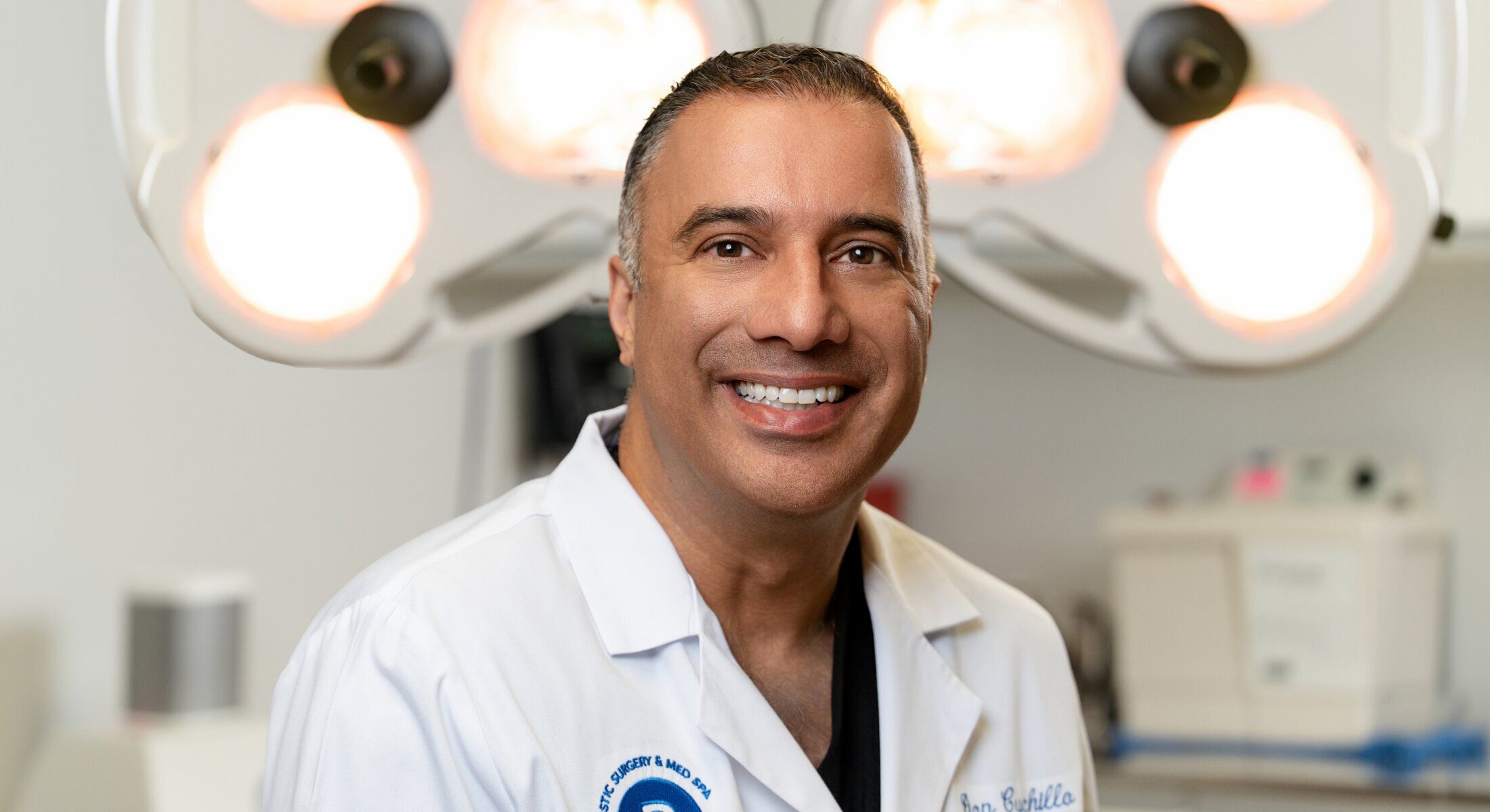 Smiling doctor in surgical environment with lights.