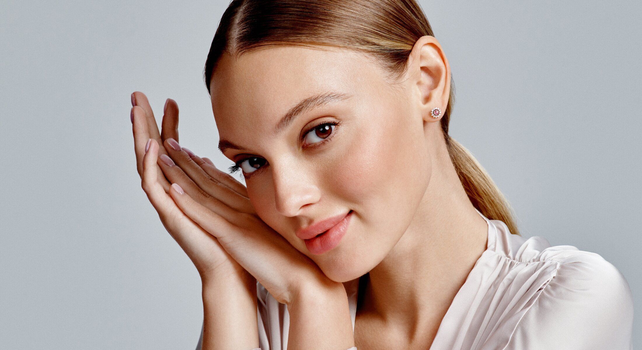 Woman with soft smile cradling her face.